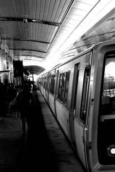 people are walking on the platform next to a train