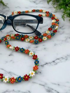 a pair of glasses sitting on top of a marble counter covered in beads and flowers