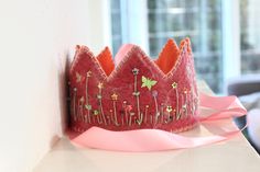 a pink crown sitting on top of a white counter next to a window sill