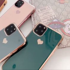 three iphones sitting next to each other on top of a white table with pink and green cases