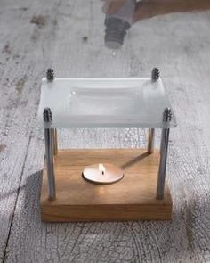 a small glass candle holder on a wooden stand with a person's feet in the background