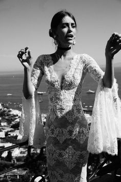 a woman in a dress standing on top of a building with her hands up to the sky