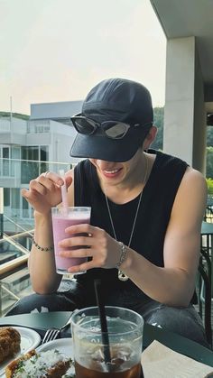 a person sitting at a table with food and drinks in front of them, wearing a hat