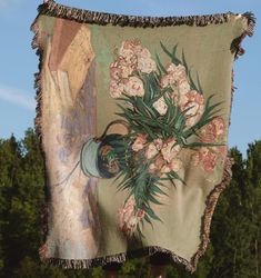 an old tapestry with flowers on it hanging from a wooden pole in front of trees