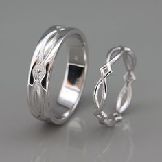 two wedding bands made out of silver with an intricate design on the inside and outside