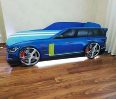 a blue car shaped bed sitting on top of a hard wood floor