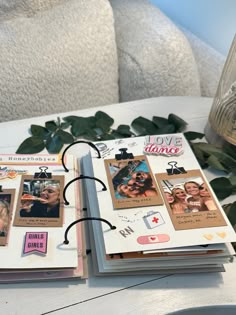 an open book sitting on top of a white table next to a vase filled with flowers