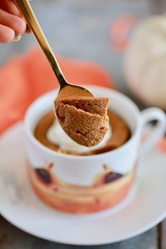 a spoon with some food in it on a white plate next to a cup and saucer