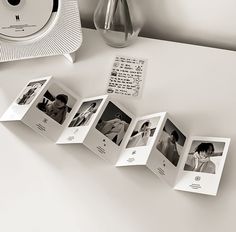 an open photo album sitting on top of a table next to a clock and vase