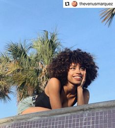 a woman laying on the edge of a swimming pool with palm trees in the background