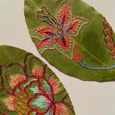 two green leaves with flowers painted on them