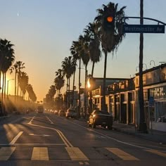 palm trees line the street as the sun sets in an otherwise empty area with no traffic