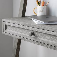 an open laptop computer sitting on top of a wooden desk next to a pencil holder