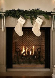 two stockings hanging over a fireplace with candles