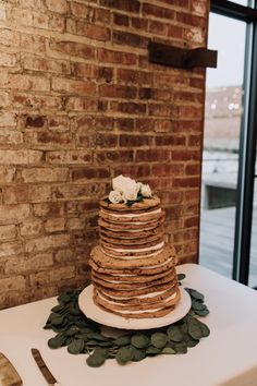 a wedding cake sitting on top of a table next to a brick wall and window