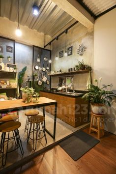 an open kitchen and dining area with wooden flooring, potted plants on the counter