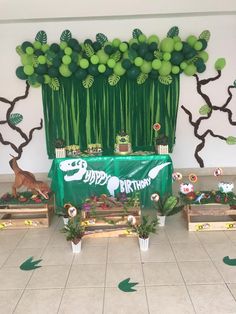 an indoor party with balloons and decorations on the wall, including green plants and trees