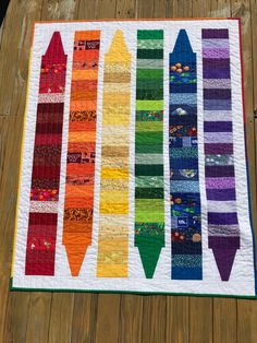 a multicolored tie quilt hanging on a wooden table with wood planks in the background