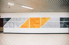 an empty room with white tile floors and orange squares on the wall, in front of a tiled floor