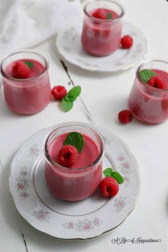 two glasses filled with raspberry smoothie on plates