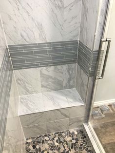 a walk in shower sitting next to a tiled floor and white walls with gray tiles