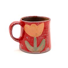 a red coffee mug with an orange flower painted on it