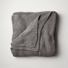 a gray crocheted blanket on top of a white table