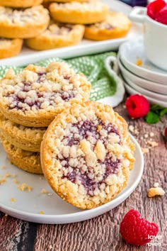 raspberry crumb cookies on a white plate with fresh raspberries in the background