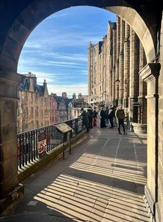 people are walking down the sidewalk in an arch