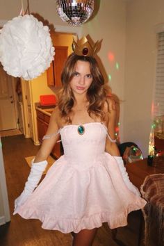 a woman in a pink dress and tiara posing for the camera with her hands on her hips