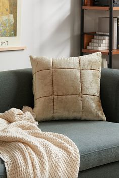 a couch with a blanket on top of it next to a book shelf and bookshelf