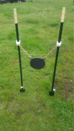 an empty swing set in the middle of a grassy field with two chains attached to it