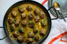 a skillet filled with meatballs and gravy on top of a table