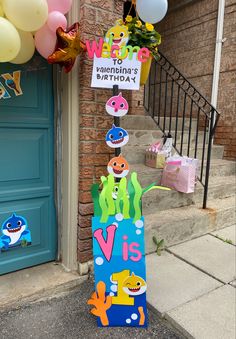 a birthday sign on the front steps of a house with balloons and streamers around it