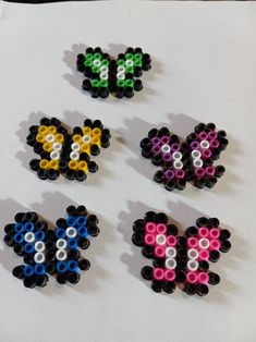 four different colored beads are arranged in the shape of hearts on a sheet of paper