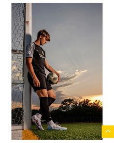 a young man holding a soccer ball next to a goalie net on a field