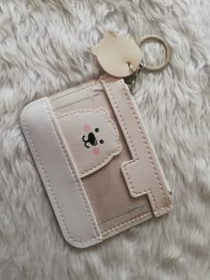 a small wallet with a koala face on it's front pocket and a keychain hanging from the side