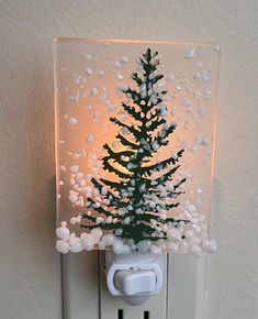 a christmas tree is placed on top of a light switch cover in the shape of a snowflake