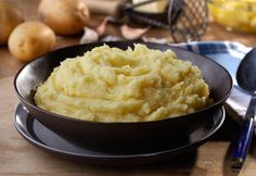 a bowl filled with mashed potatoes sitting on top of a table next to other food