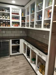 a kitchen with white cabinets and shelves filled with food