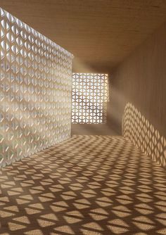 shadows cast on the wall and floor in an empty room with geometric design covering it