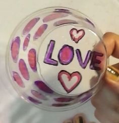 someone is holding a glass ball with the word love painted on it in pink and purple