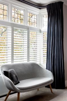 a couch sitting in front of a window with blinds on it's windowsill