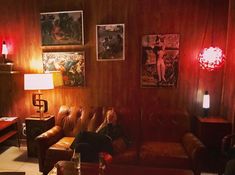 a woman sitting on a couch in a living room with red light coming from the ceiling