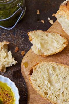 some bread is cut in half and sitting on a cutting board next to a jar of olive oil