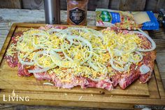 an uncooked pizza sitting on top of a wooden cutting board next to a bottle of beer