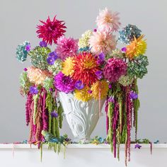 a white vase filled with lots of colorful flowers