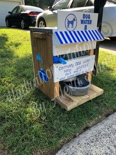 a dog water dispenser in the grass with a sign on it that says,