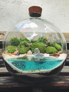 a fish bowl filled with water and rocks on top of a wooden table next to a wall