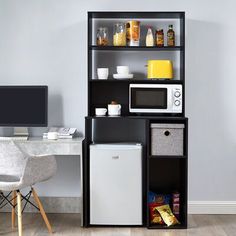 an office with a microwave, refrigerator and computer on the desk in front of it